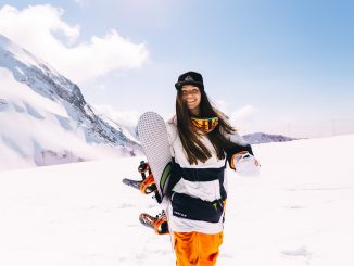 Girl holding a snowboard on the snow