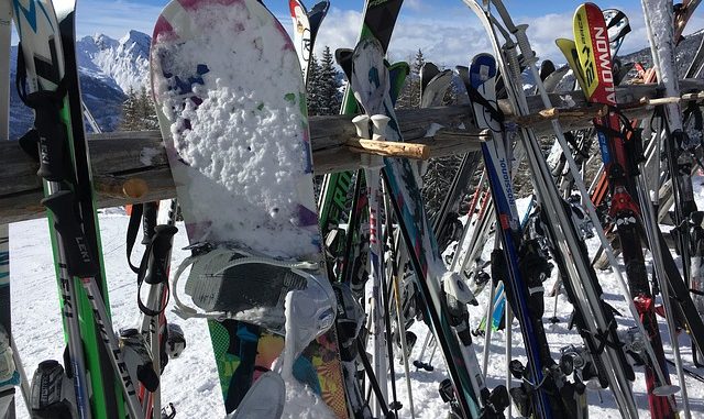 skis and snowboards on a rack while skiers dine at mountaintop restaurant